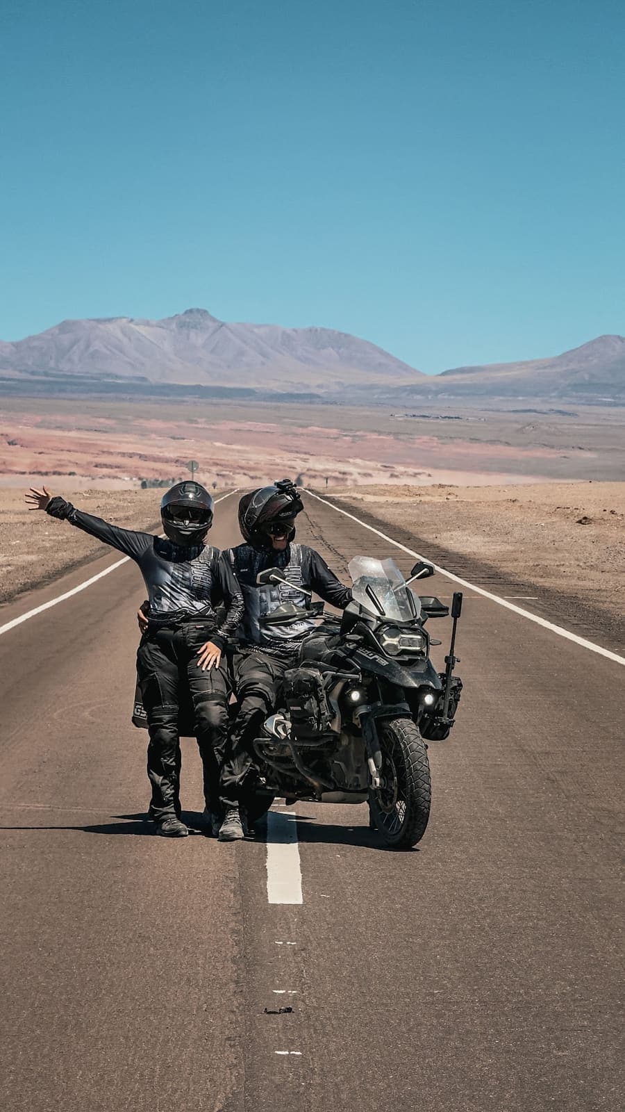 Em pé ao lado da moto numa reta no deserto